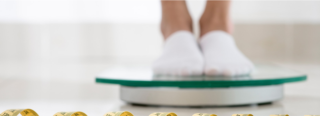 Person checking weight on a scale, questioning calorie deficit.